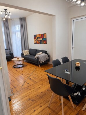 A modern living room with a sofa, a coffee table, and a dining table with chairs. - NDK Top Center Sofia Two Bedroom Apartment with ACC (Sofia)