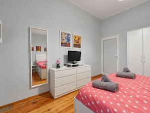 A bedroom with a bed, a dresser, a television, a mirror, and artwork on the wall. - NDK Top Center Sofia Two Bedroom Apartment with ACC (Sofia)
