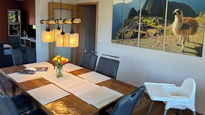 Ein Essbereich mit Holztisch, Stühlen, einer Blumenvase und einem großen Wandbild einer Lamas.