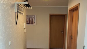 Ein Korridor mit Holzboden, einer weißen Bank, einem an der Wand befestigten Telefon und einer Tür am Ende.