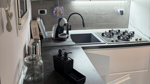 A modern kitchen with a gas stove, a coffee maker, and a water dispenser.