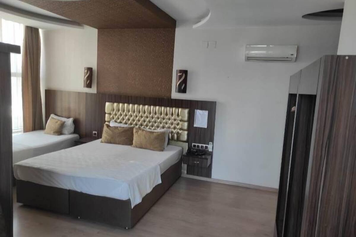 A modern hotel room with a large bed, a bedside table, and a built-in air conditioning unit.