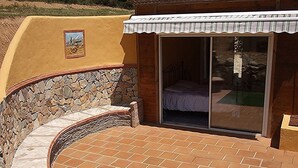 Een terras met stenen muren en een bed zichtbaar door een schuifdeur.