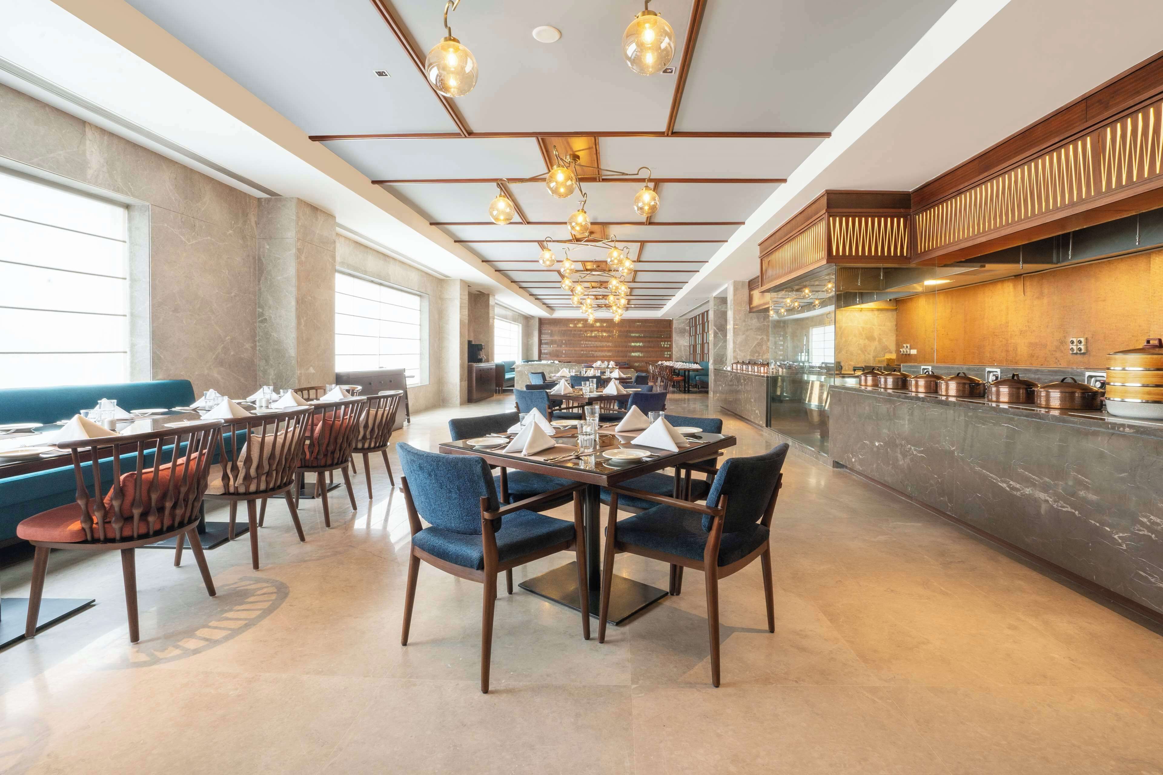 A modern dining area with a long table set for a meal, surrounded by blue upholstered chairs.