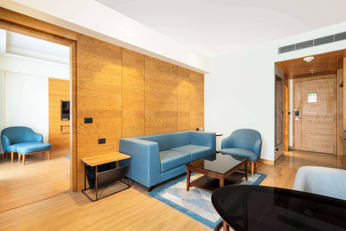 Un salon moderne avec un canapé bleu, deux fauteuils, une table basse et un mur d’accent en bois.