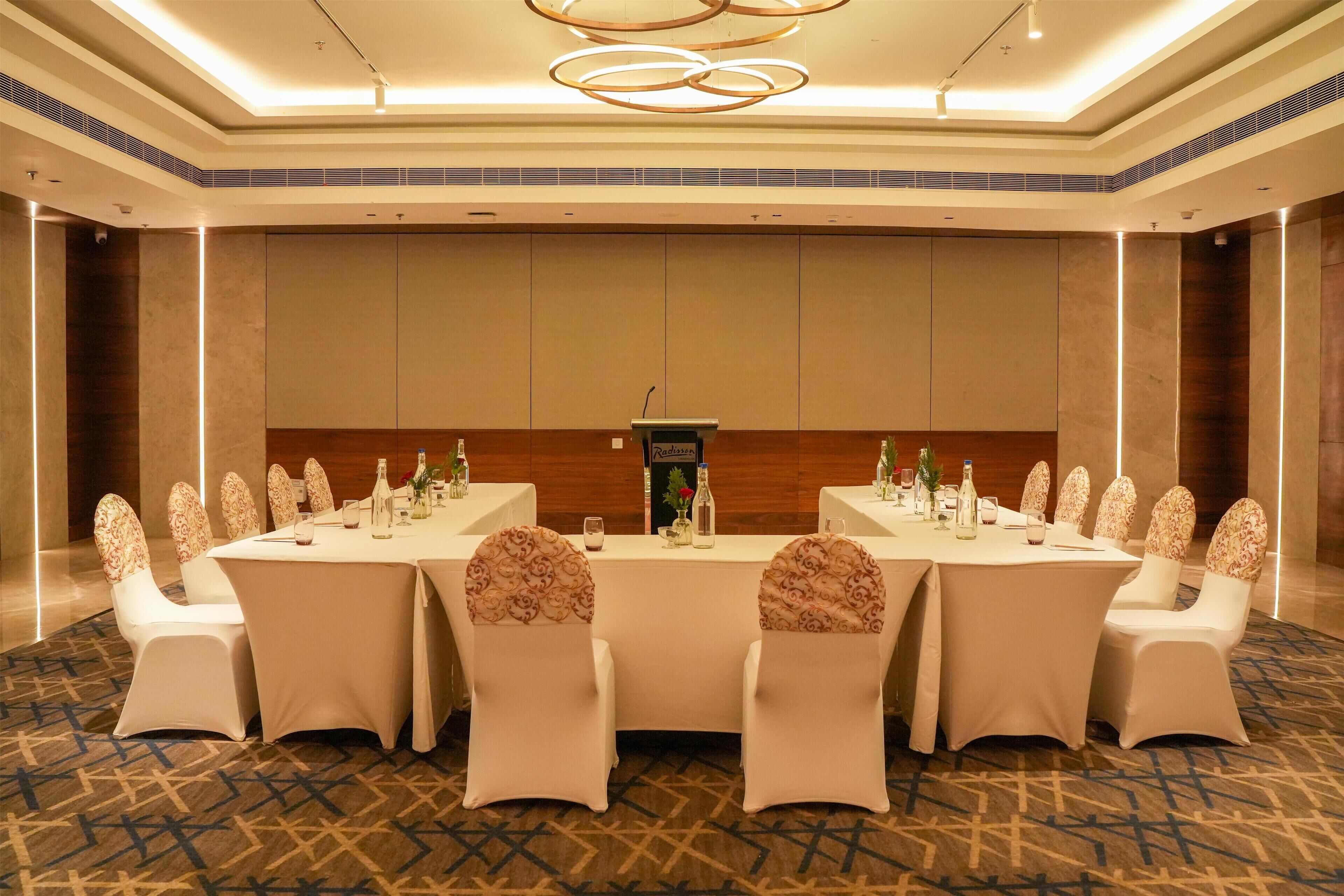A conference room with a long table, white chairs, and a podium.