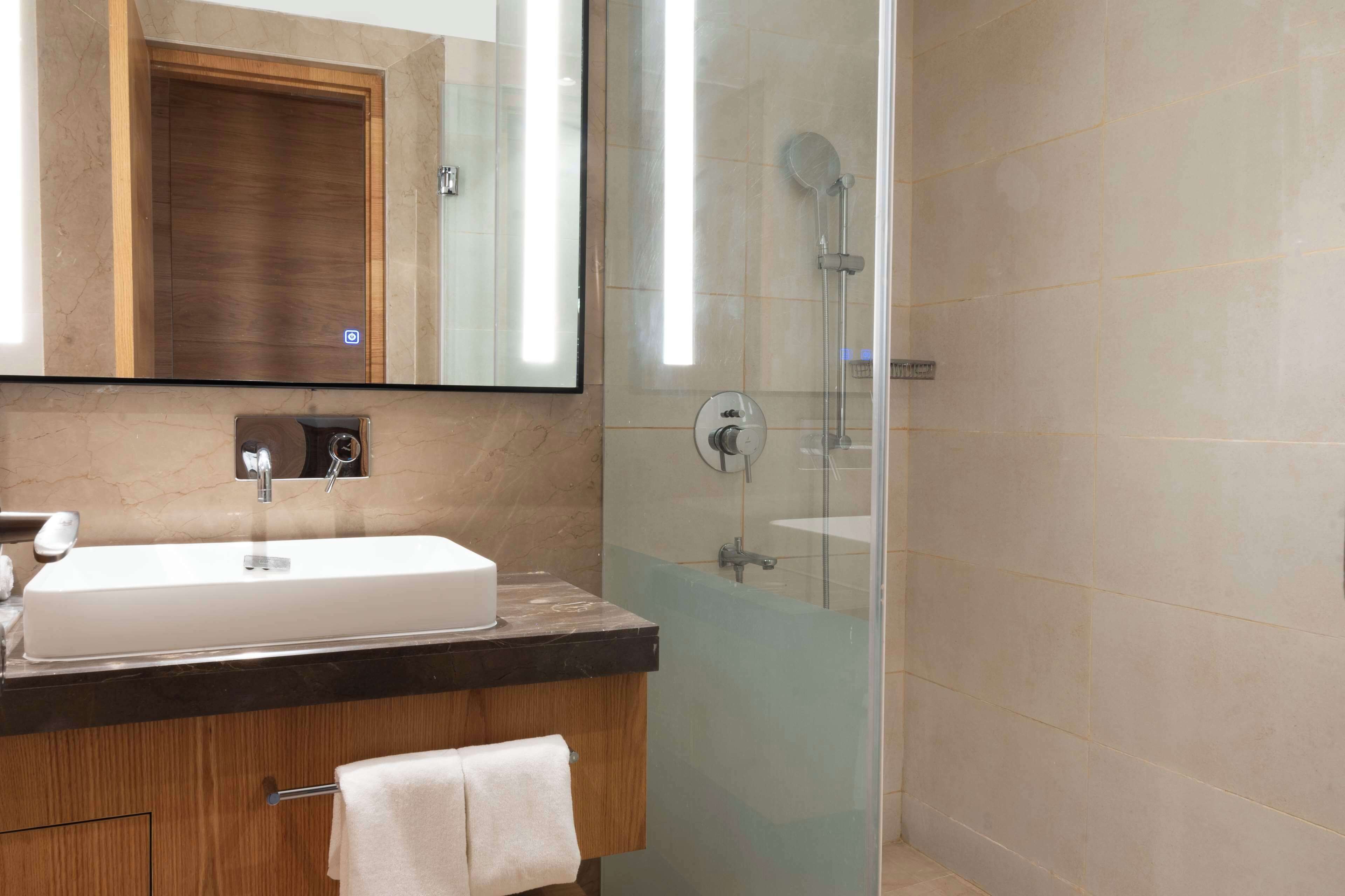 Une salle de bain moderne avec un grand miroir, un lavabo et une douche à parois de verre.