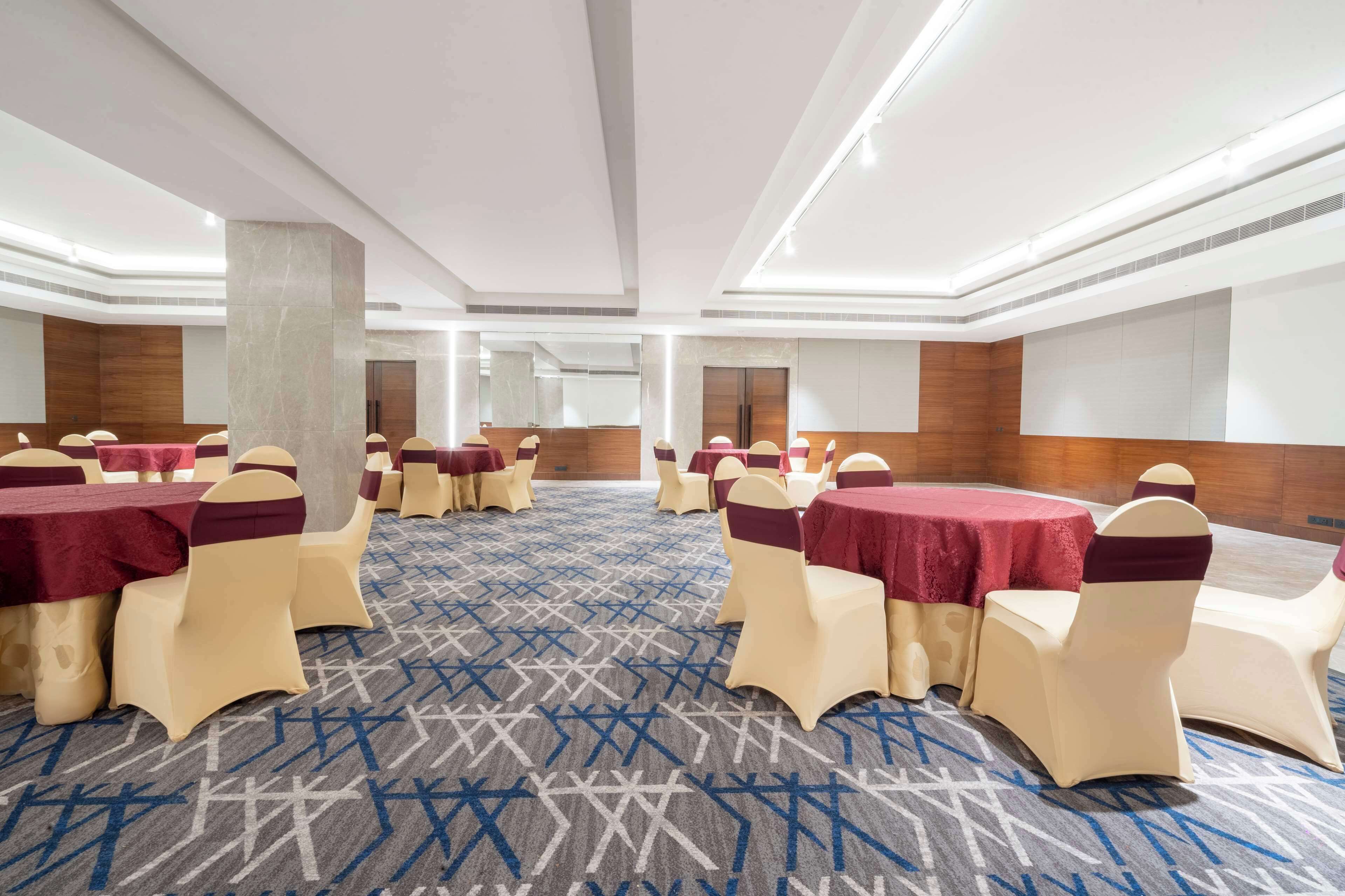 A conference room with multiple tables and chairs, carpeted floor, and wooden panel walls.