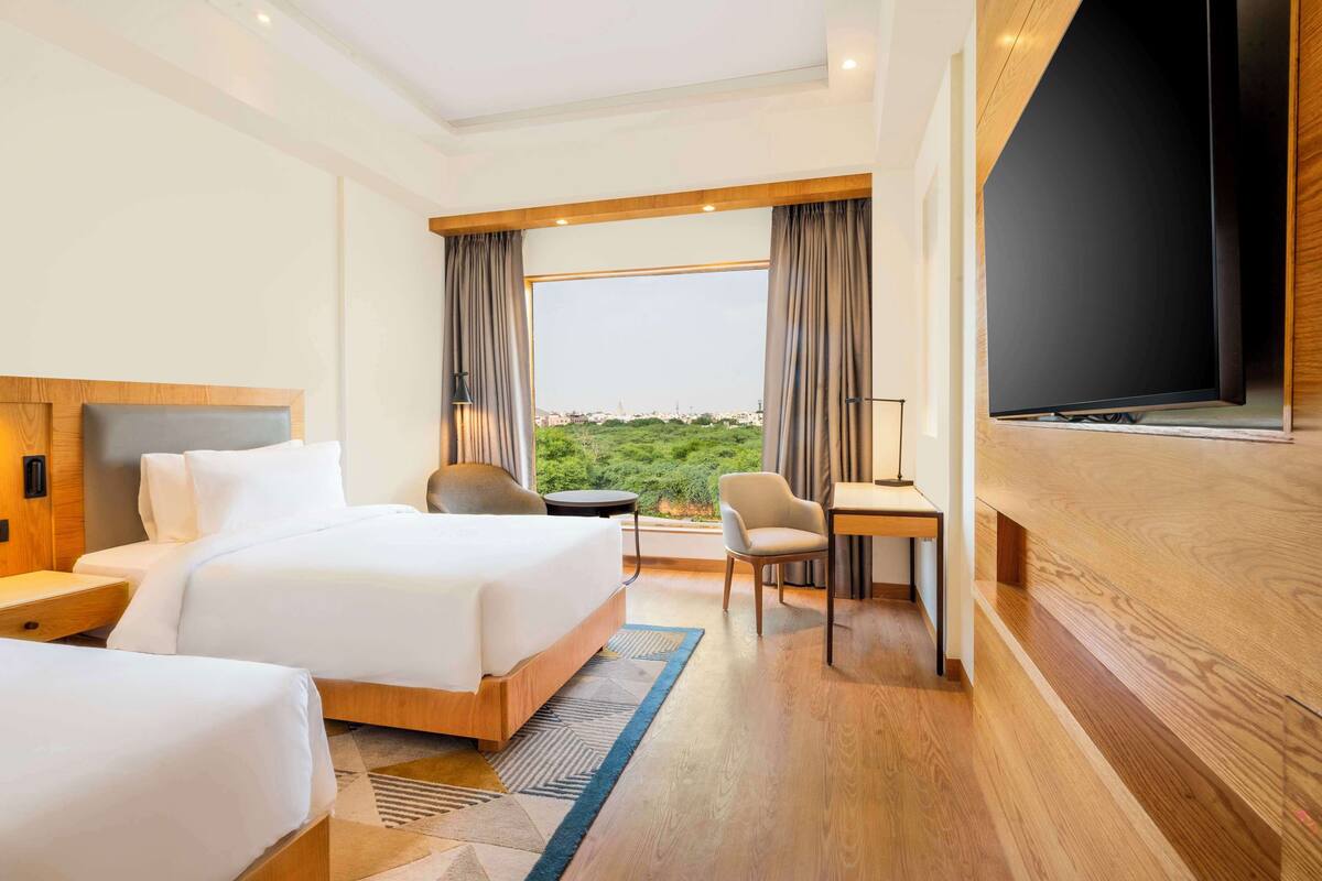 Une chambre d’hôtel avec un grand lit, un bureau, une chaise et un téléviseur.