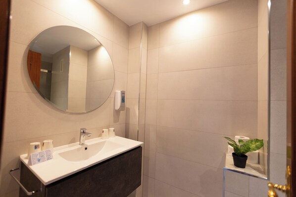Un baño moderno con un espejo redondo, un lavabo y una pequeña planta en maceta.