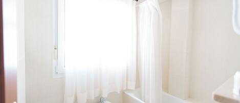 A bathroom with a toilet, bidet, bathtub, and a sink.
