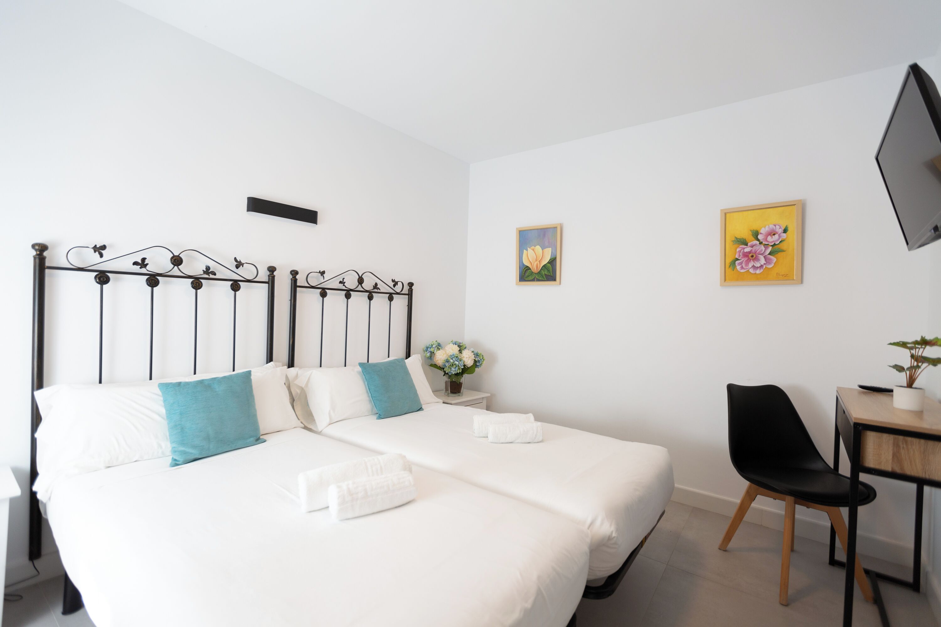 A neatly arranged bedroom with a bed, bedside table, chair, and a TV mounted on the wall.