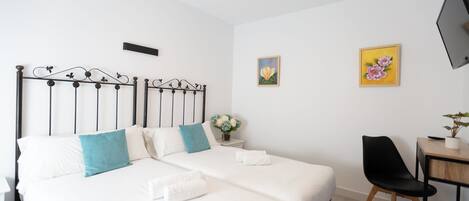 A neatly arranged bedroom with a bed, bedside table, chair, and a TV mounted on the wall.