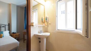 Un baño de hotel con cama, lavabo y ventana.