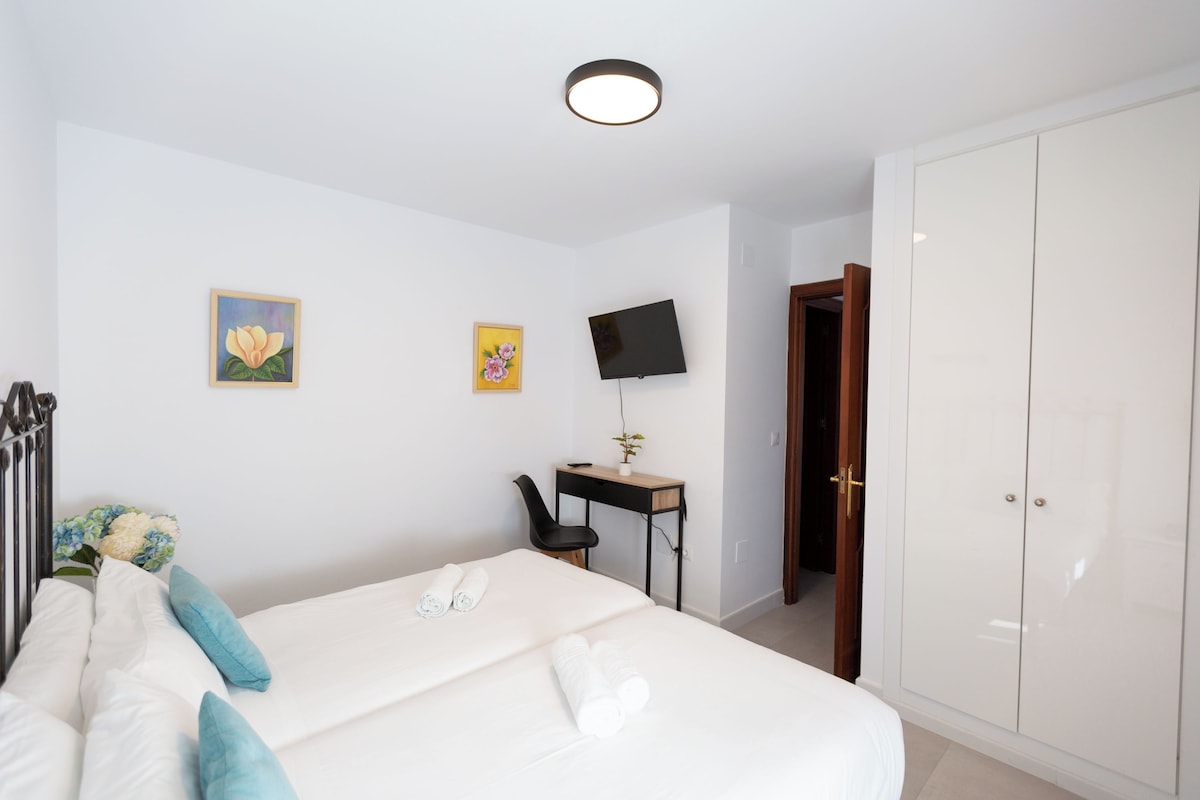 A hotel room with a bed, a desk with a computer, a TV, and a wardrobe.