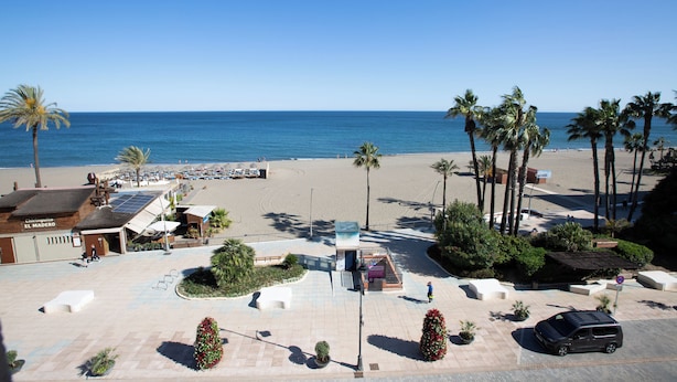 A beachside hotel with a patio area, palm trees, and a view of the ocean. - Hotel Mediterraneo by Croma (Estepona)