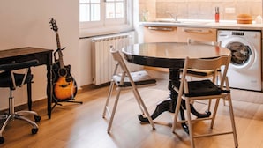 A compact kitchen with a dining table, chairs, a guitar, and a washing machine. - The Bright Nest Aquarium - Genoa Historical Center (Genova)
