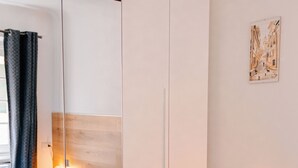 A modern hotel room with a large bed, a wardrobe, a bedside table with a lamp, and a wall-mounted artwork. - The Bright Nest Aquarium - Genoa Historical Center (Genova)