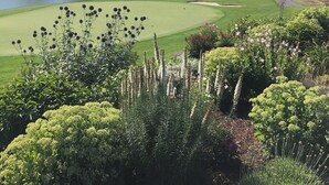 Ein Golfplatz mit Teich, Bäumen und einer Brücke.