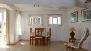 A dining area with a table and chairs, a lamp, and a chair with a cushion. - Apartamento Paco Romo (Nerja)