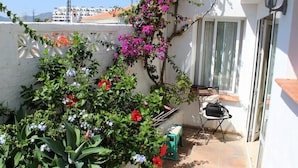 A small outdoor area with a white wall, a window, and a door. There is a chair and a small table. - Apartamento Paco Romo (Nerja)