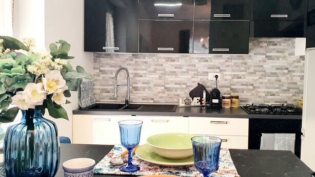 A modern kitchen with black cabinets, a tiled backsplash, and a gas stove. - Lemon Sunshine Ciampino (Ciampino)