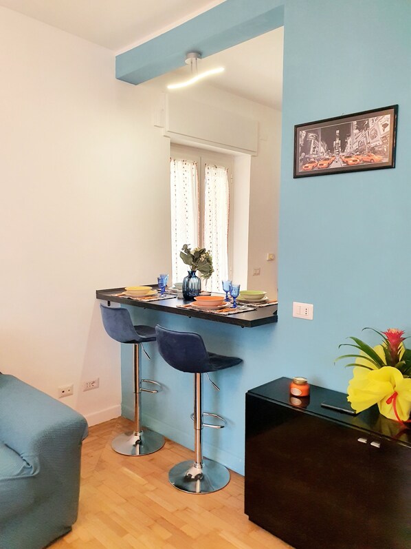 Cozinha moderna com área de bar, dois banquetes, uma mesa de jantar e uma planta decorativa.