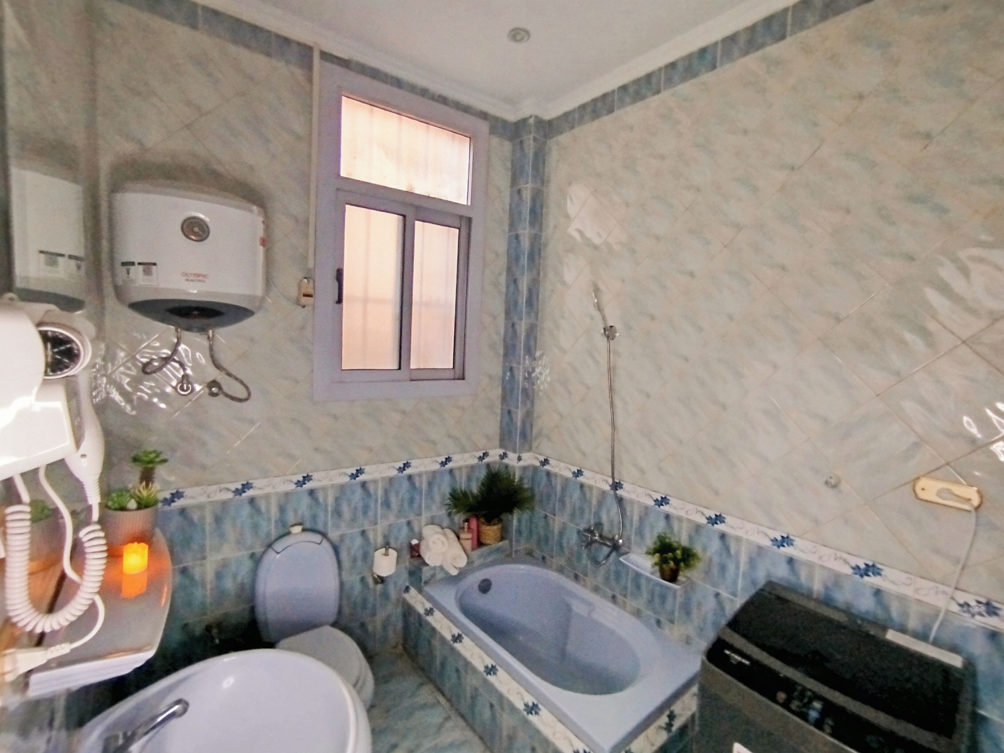 Une salle de bain avec des toilettes, un lavabo, une baignoire et une fenêtre.
