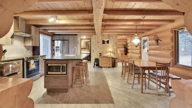 L’intérieur d’une cabane en rondins comprend une cuisine, un coin repas et un bar.