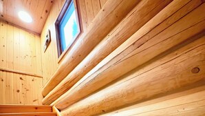 Un escalier en bois, doté d’une rampe, mène à une pièce aux murs en bois et pourvue d’une fenêtre.