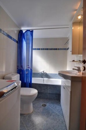 A bathroom with a toilet, bathtub, and sink. - Memories of Milos (Milos)