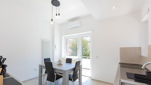 Moderni keittiö, jossa on ruokailutila, suuri ikkuna, sisäänrakennettu uuni ja pesuallas.