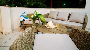 A balcony with wicker furniture, a sofa, a table, and a vase with flowers. - Apartment Nonna (Seget)