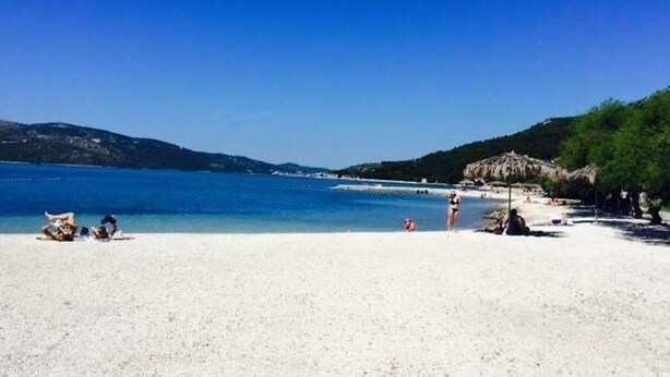 A beach with clear blue water, white sand, and a few people. - Apartment Nonna (Seget)