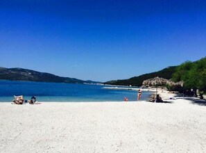 A beach with clear blue water, white sand, and a few people. - Apartment Nonna (Seget)