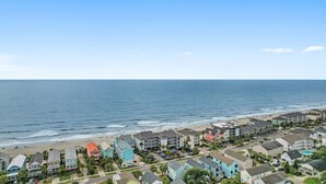 A coastal residential area with beachfront properties, including multi-story buildings and single-family homes, with a clear view of the ocean. - 4BR Home w/ Free Linens & Beach Access (Surfside Beach)