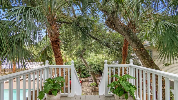 A wooden deck with white railings leading to a patio area with outdoor furniture and potted plants. - 4BR Home w/ Free Linens & Beach Access (Surfside Beach)