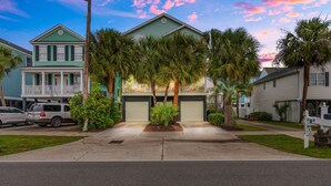 A residential street with houses, palm trees, and a clear sky. - 4BR Home w/ Free Linens & Beach Access (Surfside Beach)