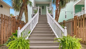 A staircase leading to a house with a wooden fence on both sides and two potted ferns at the bottom. - 4BR Home w/ Free Linens & Beach Access (Surfside Beach)
