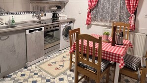A compact kitchen with a dining area, featuring a checkered tablecloth, wooden chairs, and a tiled floor. - Gemütliche Unterkunft Zentral in Oberwinter mit Balkon (Remagen)