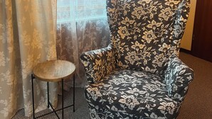 A room with a floral-patterned armchair and a small round table. - Gemütliche Unterkunft Zentral in Oberwinter mit Balkon (Remagen)