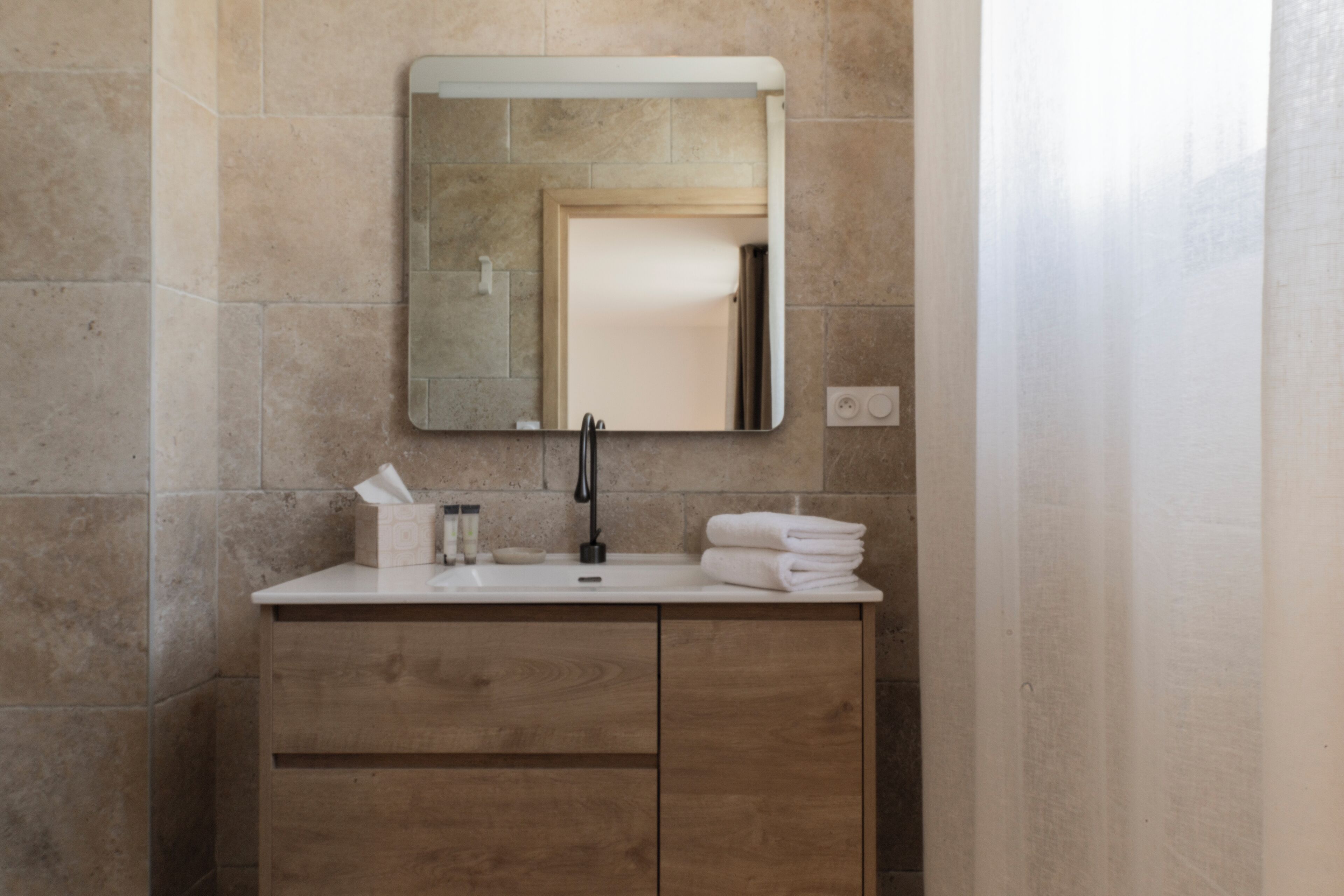A bathroom with a wooden vanity, a mirror, and a sink.