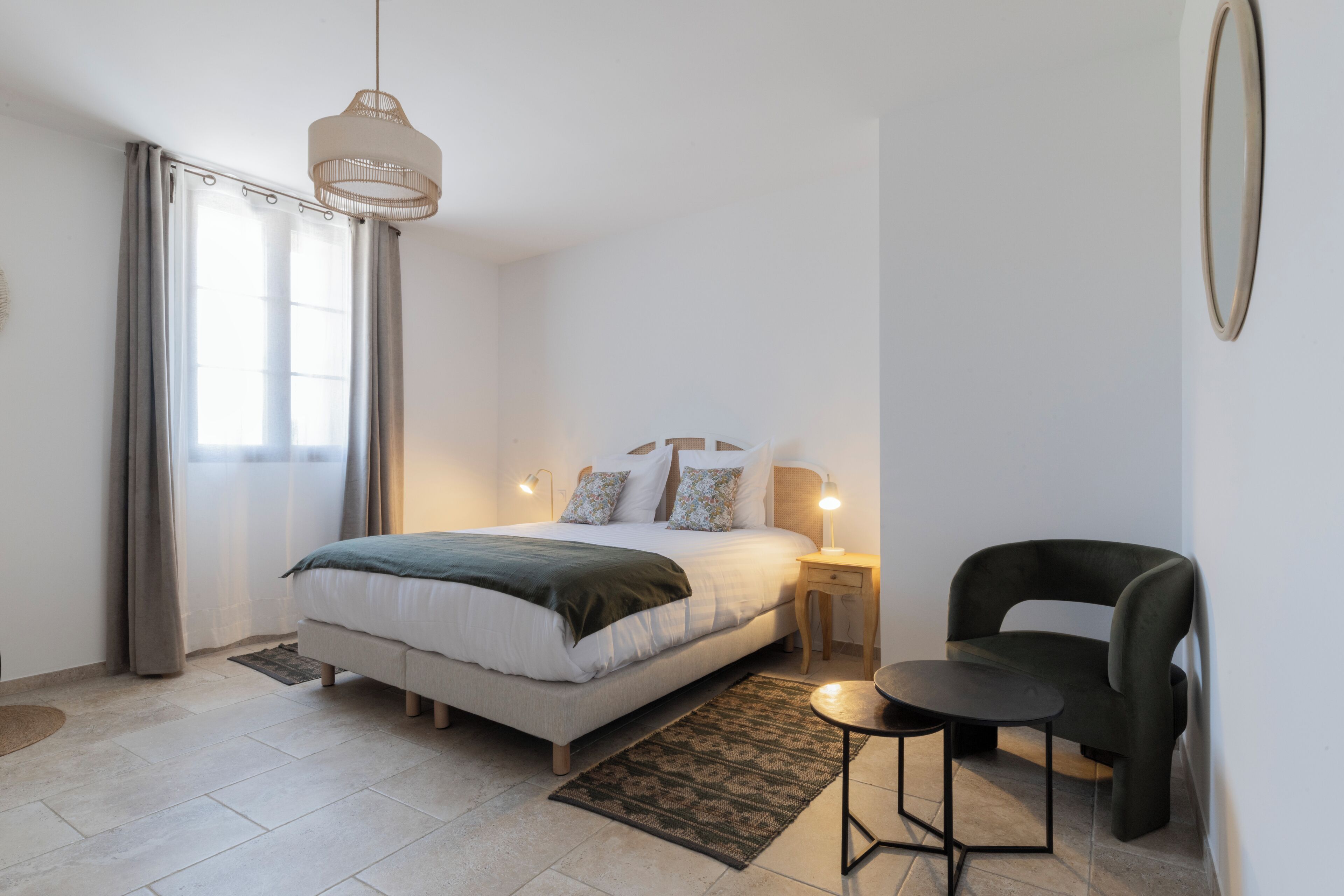 Quarto com uma cama, luminárias de cabeceira, uma cadeira e uma pequena mesa.