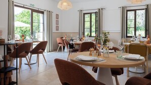 A dining area with round tables, brown chairs, and pendant lighting.