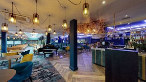 A modern bar area with a piano, seating, and a bar counter. - Rutland Hall Lakeside Lodges (Oakham)