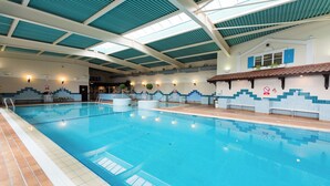 An indoor swimming pool with clear lanes, a tiled floor, and a high ceiling with skylights. - Rutland Hall Lakeside Lodges (Oakham)