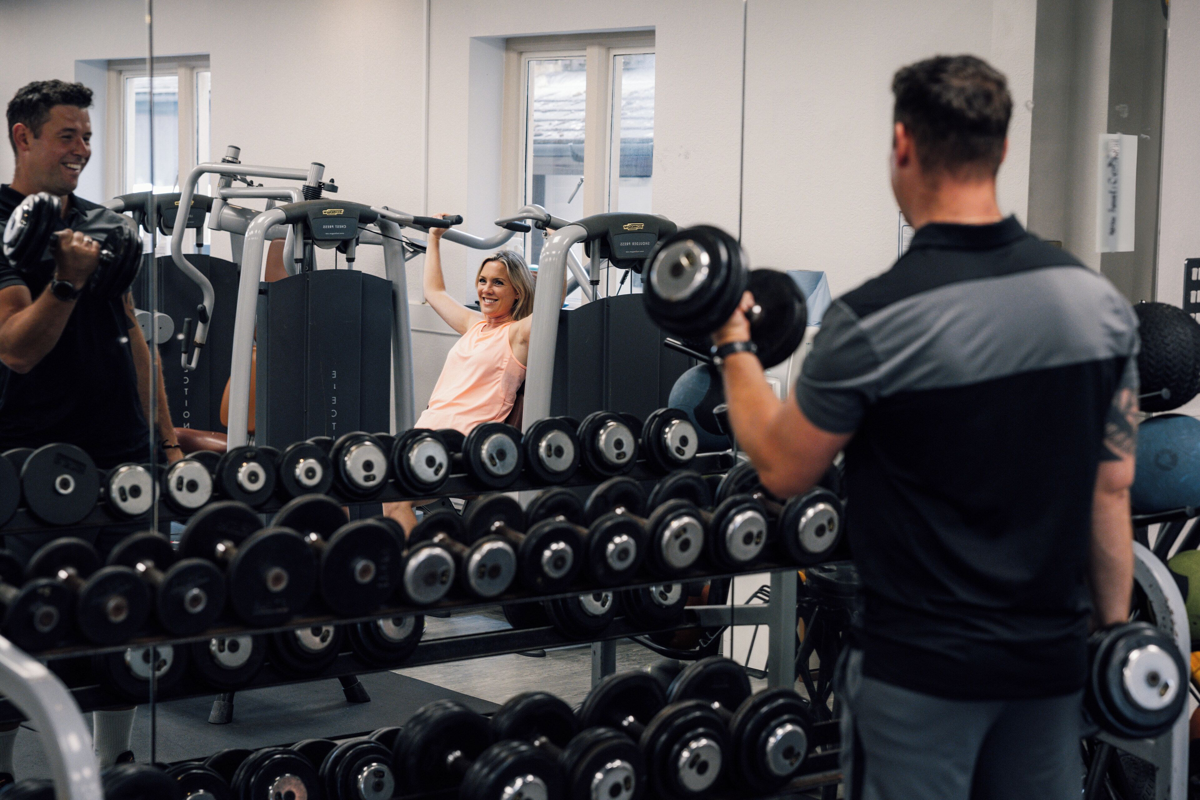 A gym with weightlifting equipment and dumbbells.