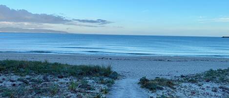 A beach path leading to the ocean with a clear sky.