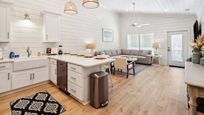 Een moderne keuken met witte kasten, een centraal eiland en hanglampen.