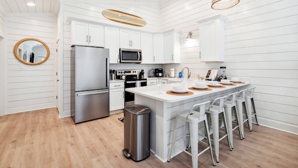 Een moderne keuken met witte kasten, roestvrijstalen apparatuur en een centraal eiland met barstoelen.